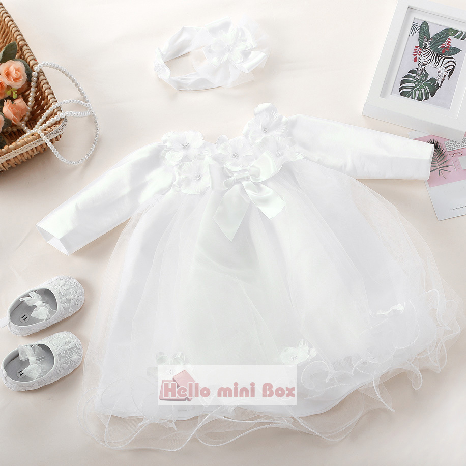 Un vestido de bautizo corto y suave con flores y lazos en el pecho.