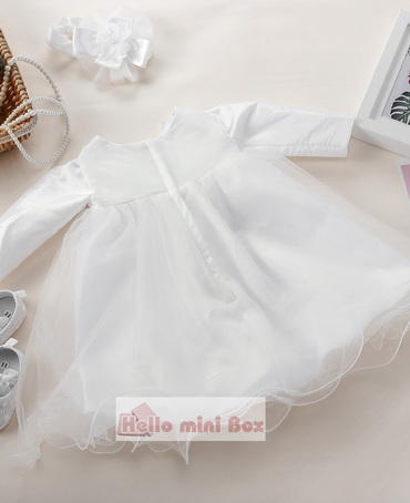 A short soft net christening dress with flowers and bows on the chest